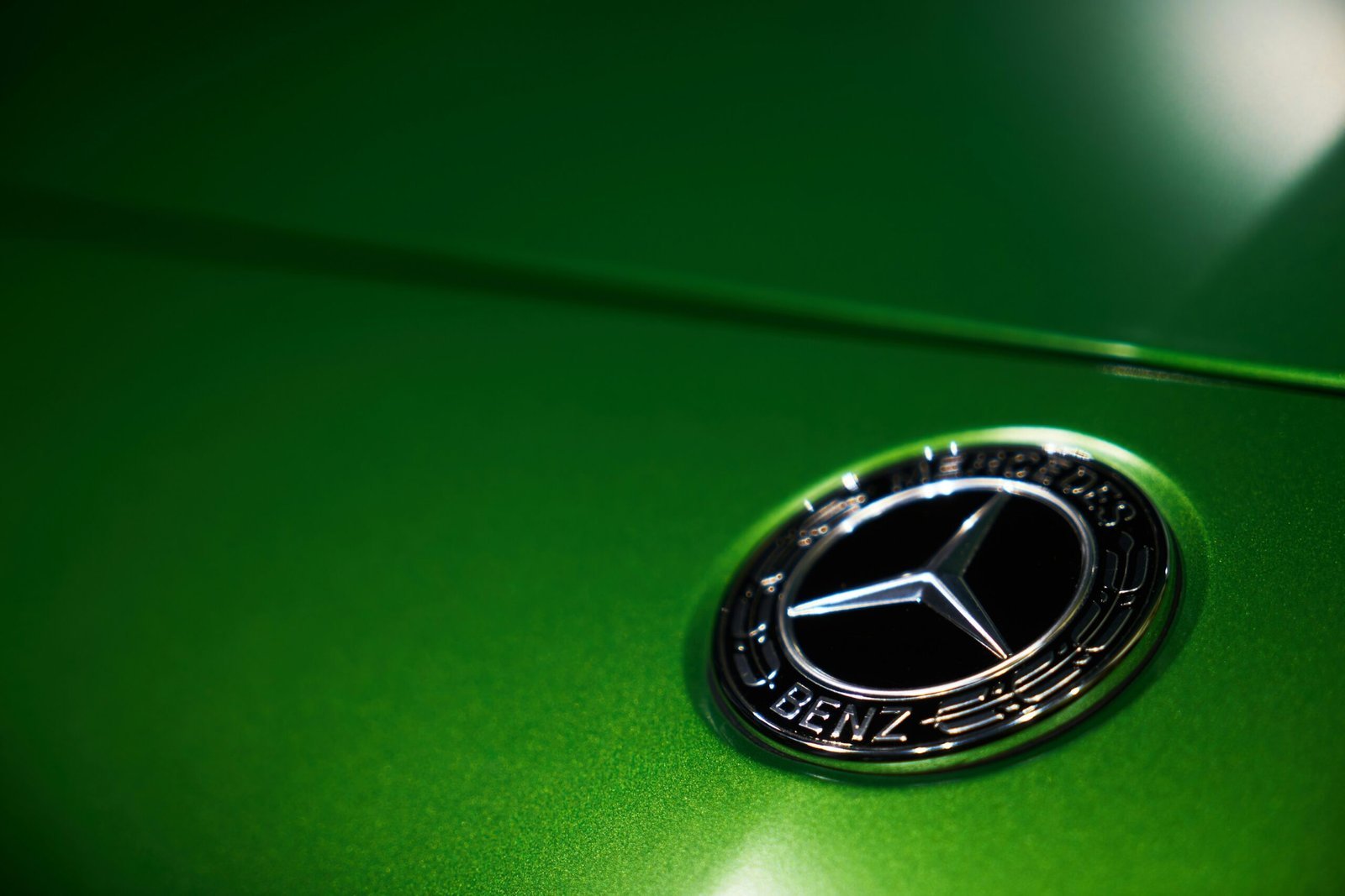 a close up of a mercedes emblem on a green car